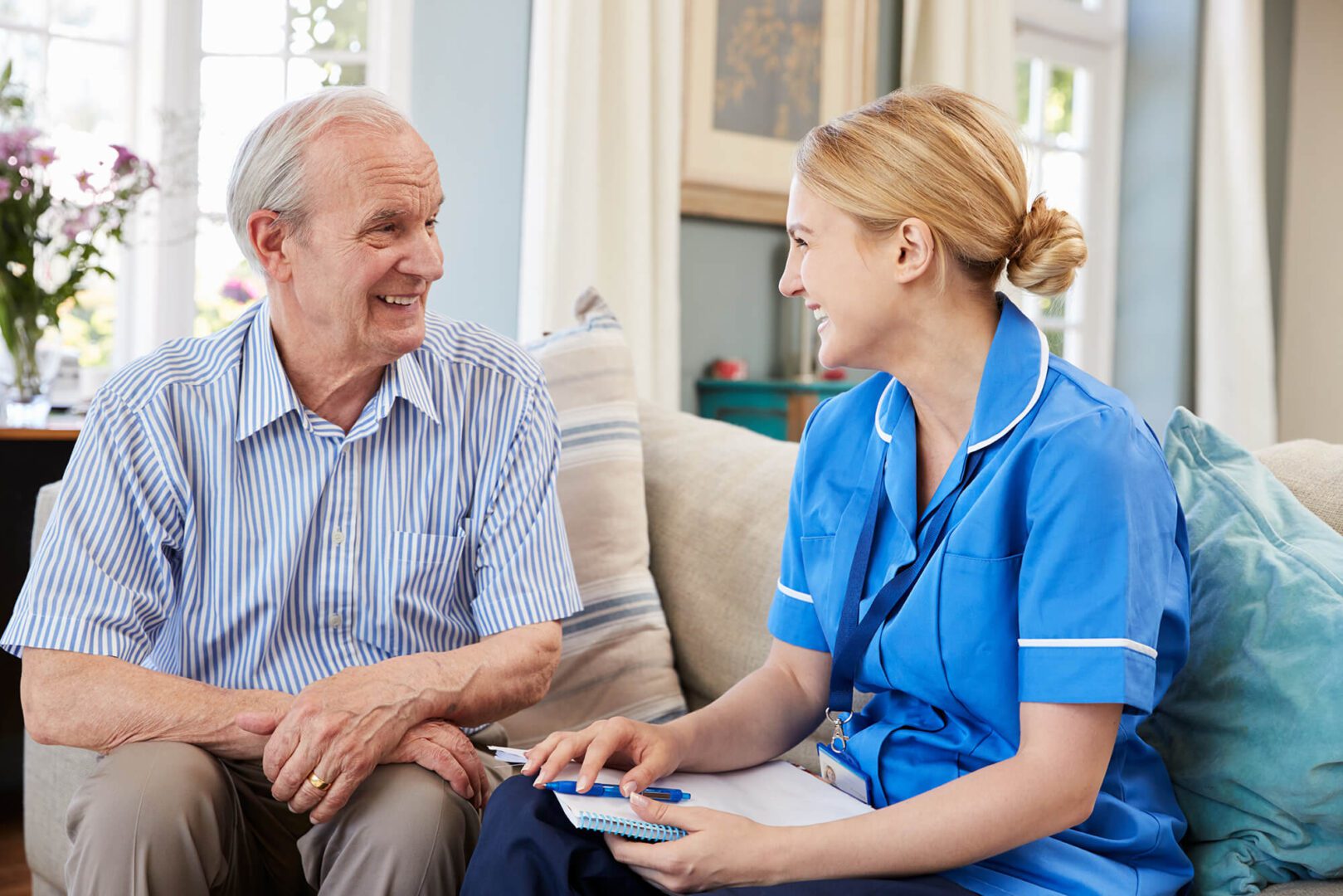 A Care Worker talking to an older man in blue shirt.