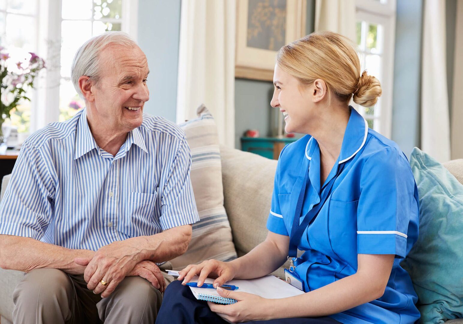 A Care Worker talking to an older man in blue shirt.